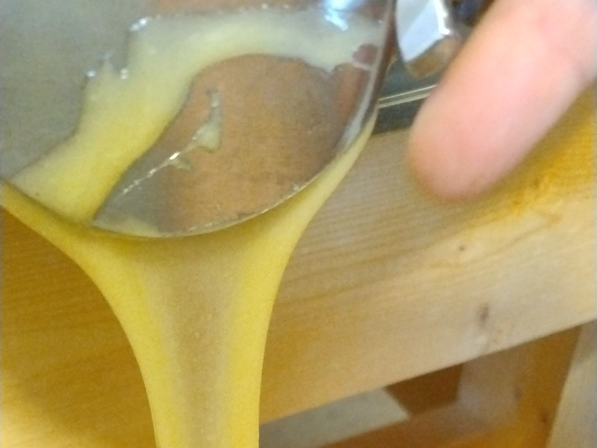 Filling a small jar by hand with thick, freshly extracted honey